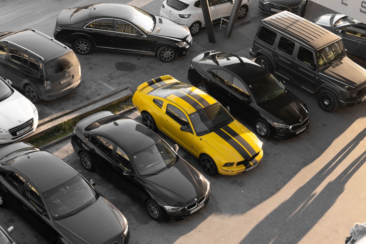 services-01 Top view of various cars parked in a parking lot, featuring a yellow sports car.