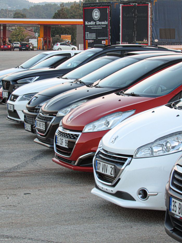 hero-img-02 Lineup of modern cars neatly parked outdoors at a dealership with visible license plates.